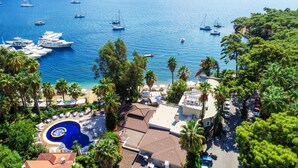 A coastal resort with a swimming pool, palm trees, and boats in the background. - Joya Del Mar Hotel (Marmaris)
