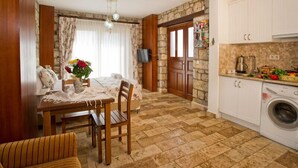 Un saló acollidor amb un sofà, una taula de dinar amb cadires, una televisió i una cuina amb rentadora.