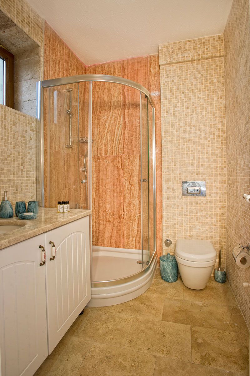 Une salle de bain avec une douche à parois de verre, des toilettes blanches et un sol carrelé.