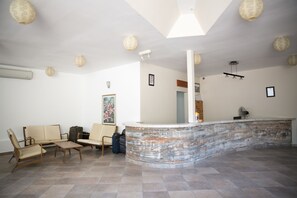 Una zona de recepción con un mostrador curvo, un sofá y dos sillones.
