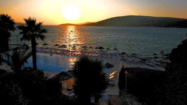 Un resort con piscina, zona de playa y vistas al atardecer.