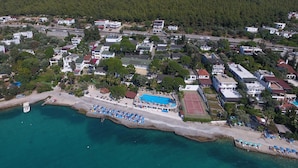 Vista aérea de un pueblo costero con playa, piscina y edificios residenciales.