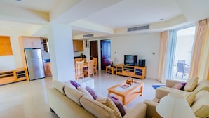 A modern living room with a sofa, coffee table, TV, and dining area. - Sea View Hua Hin Condos (Hua Hin)