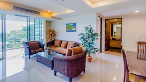 A spacious living area with a large window, a sofa, a coffee table, and a dining table. - Sea View Hua Hin Condos (Hua Hin)
