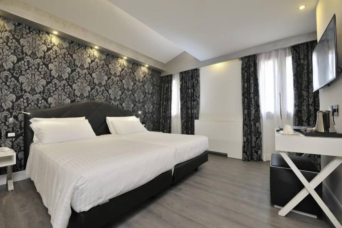 Un dormitorio moderno con una cama grande, un escritorio y una televisión.
