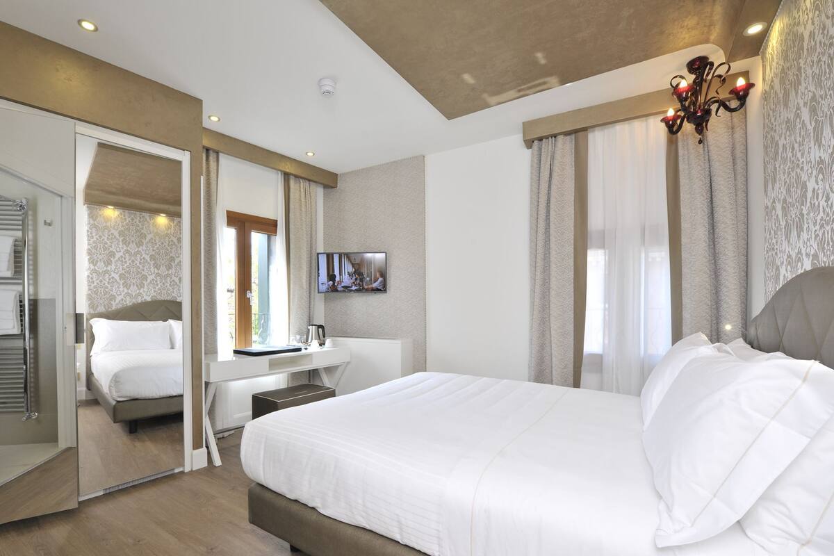 Una habitación de hotel moderna con una cama grande, un escritorio y un televisor.