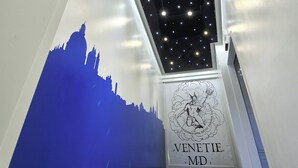 Un escalier surmonté d’un plafond étoilé et orné d’une silhouette bleue représentant une vue urbaine.
