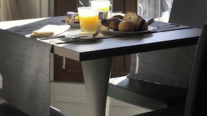 A dining table with breakfast items, a laptop, and a window with curtains. - Al Theatro Palace (Venice)