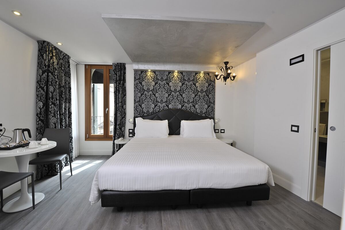 Una habitación de hotel moderna con una cama grande, una mesa de comedor y una silla.
