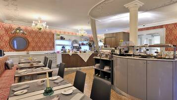 Um restaurante com área de bar, mesas redondas com cadeiras e um balcão de buffet.