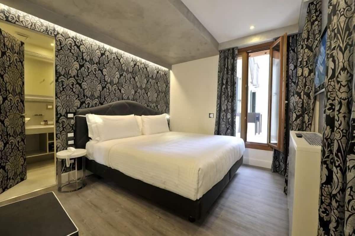 Un dormitorio con una cama grande, una mesita de noche, un espejo y un armario.
