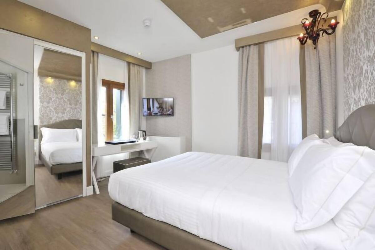 Una habitación de hotel moderna con una cama grande, un escritorio y un espejo.