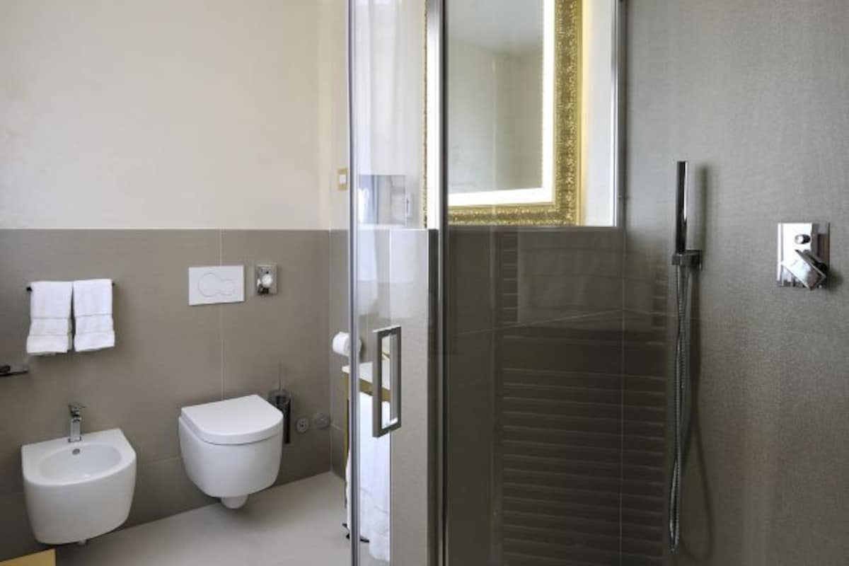 A bathroom with a glass shower enclosure, a bidet, and a toilet.