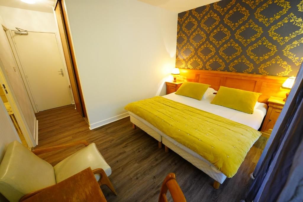 Una habitación de hotel con una cama, dos mesitas de noche, una silla y una puerta.