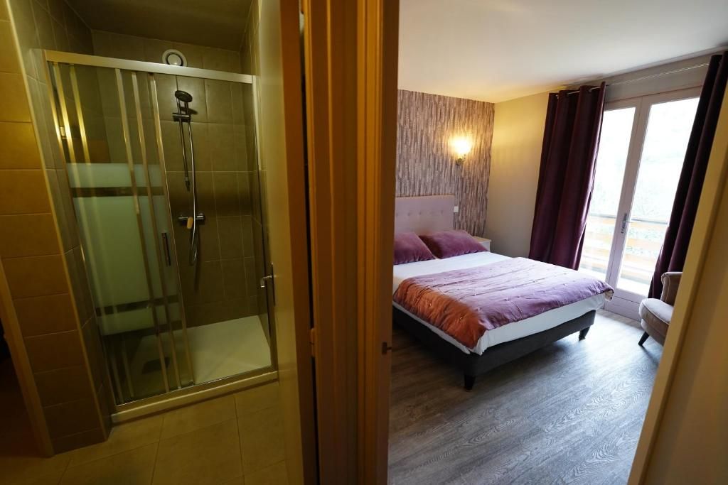 A hotel room with a shower, a bed with a headboard, and a window with curtains.