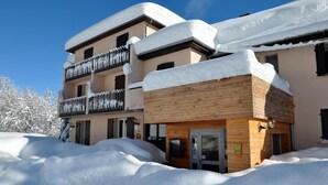 Un hotel con fachada de madera y balcones cubiertos de nieve.