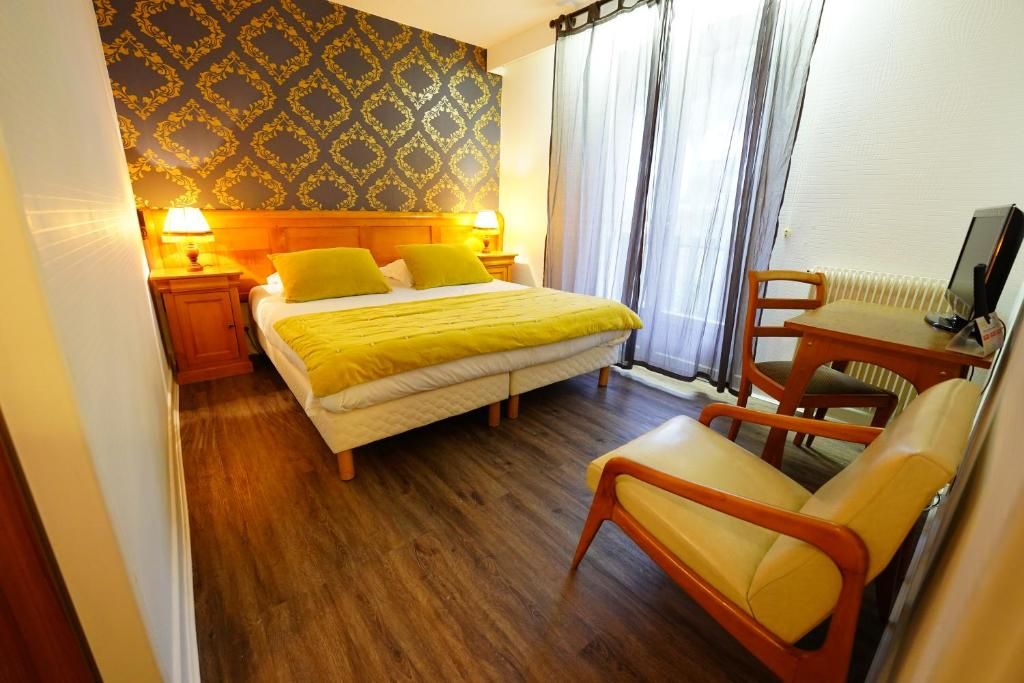 Een hotelkamer met een bed, twee bedlampen, een bureau met stoel en een raam met gordijnen.
