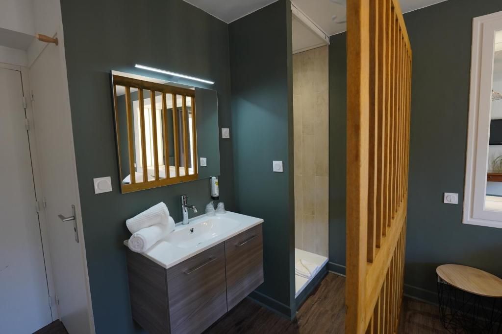 Un baño con un lavamanos blanco, un espejo con persianas verticales y un panel de madera.