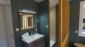 A bathroom with a white sink, a mirror with vertical blinds, and a wooden partition. - Le Griou (Saint-Jacques-des-Blats)