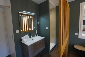 A bathroom with a white sink, a mirror with vertical blinds, and a wooden partition. - Le Griou (Saint-Jacques-des-Blats)