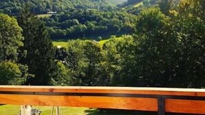 Vista de un paisaje montañoso con abundante vegetación y una valla de madera en primer plano.
