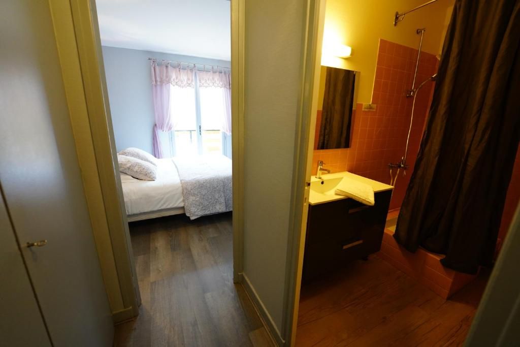 A bedroom with a bed, a bathroom with a sink and mirror, and a shower area.