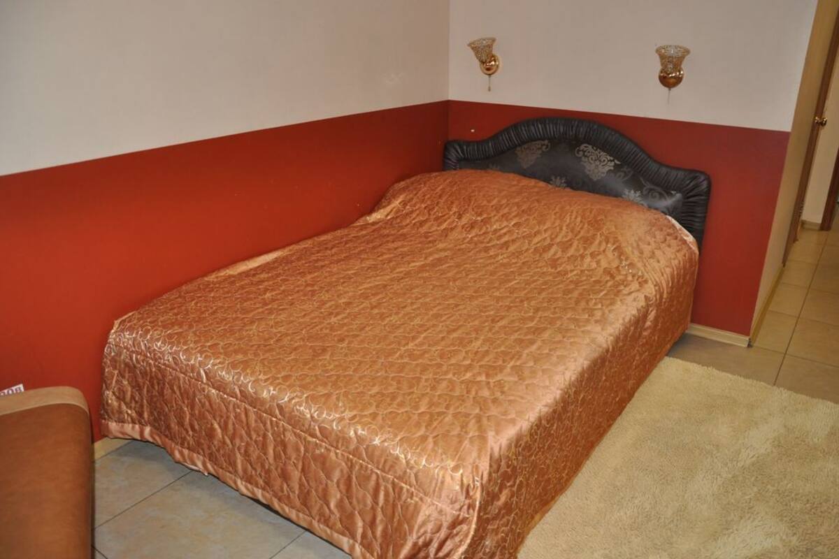 A single bed with a patterned bedspread in a room with red and white walls.