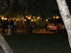 An outdoor event with tables and chairs, surrounded by trees and string lights. - Hotel Plauter Kúria (Velky Meder)