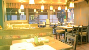 Un restaurante con cabinas y mesas, iluminación colgante y vistas a la calle.