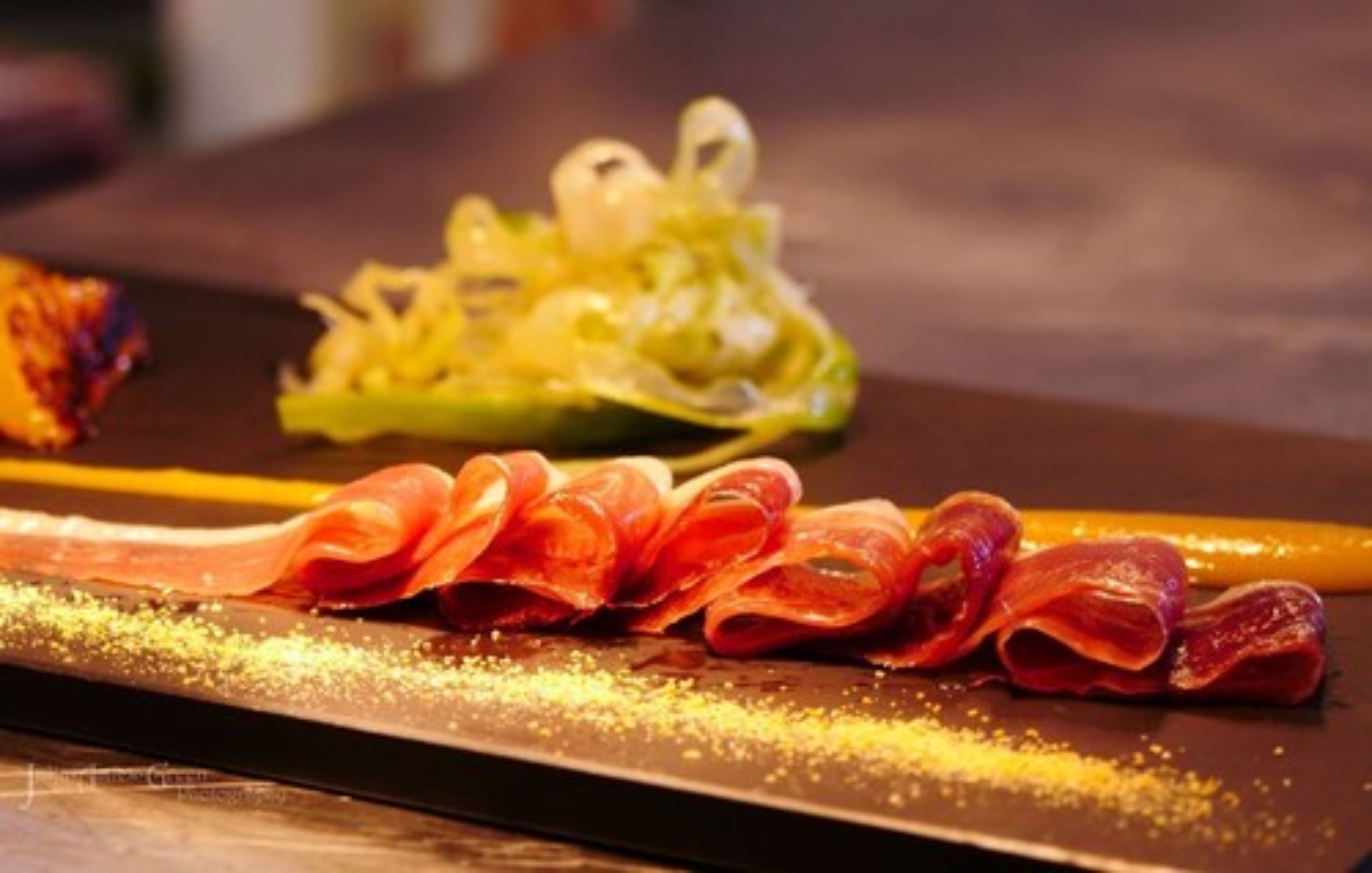 A plate of food with thinly sliced meats and a vegetable garnish.