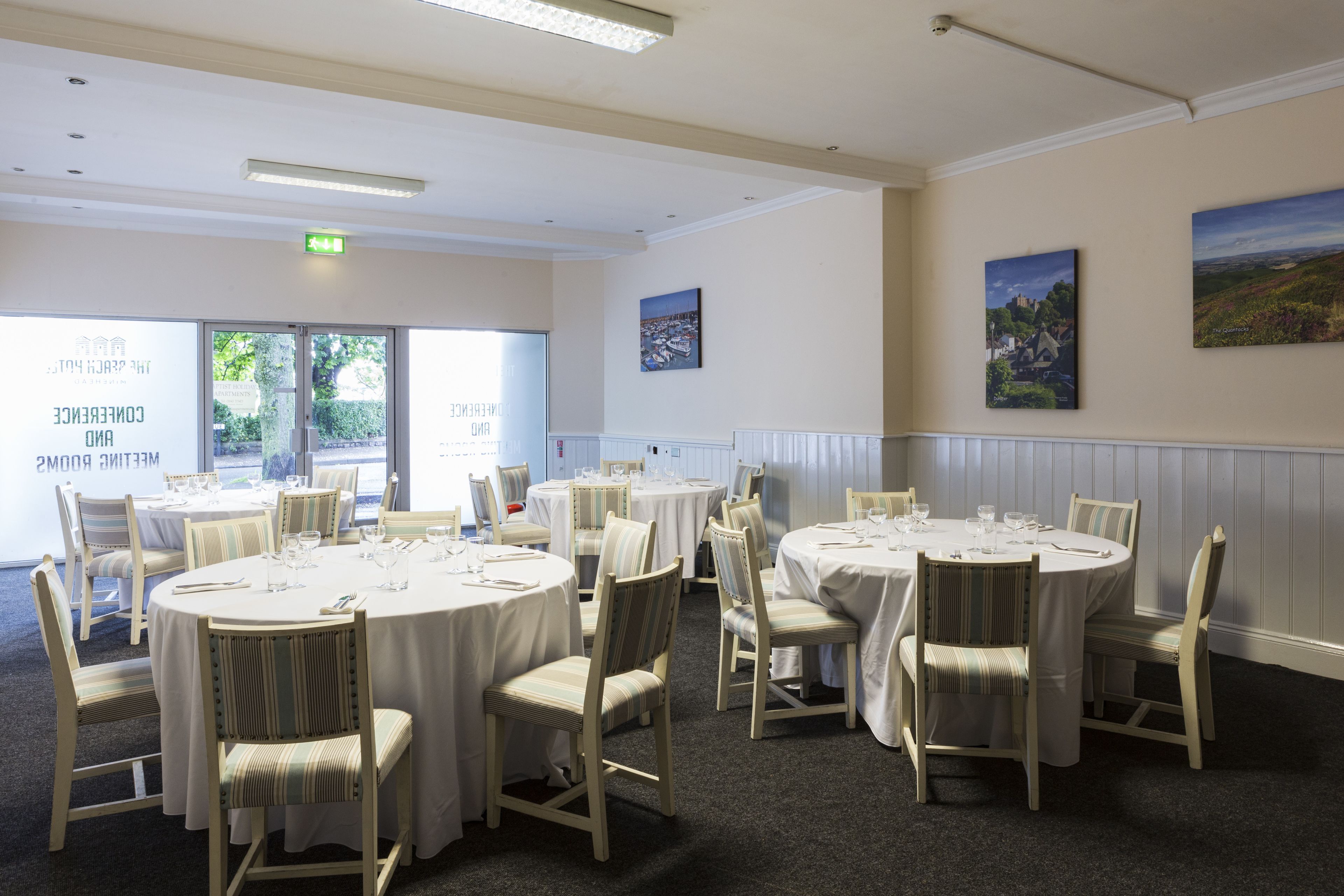 A conference room with round tables and chairs, large windows, and artwork on the walls.