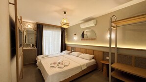 Ett hotellrum med en säng, sängbord, en spegel, en hängande lampa och en våningssäng.