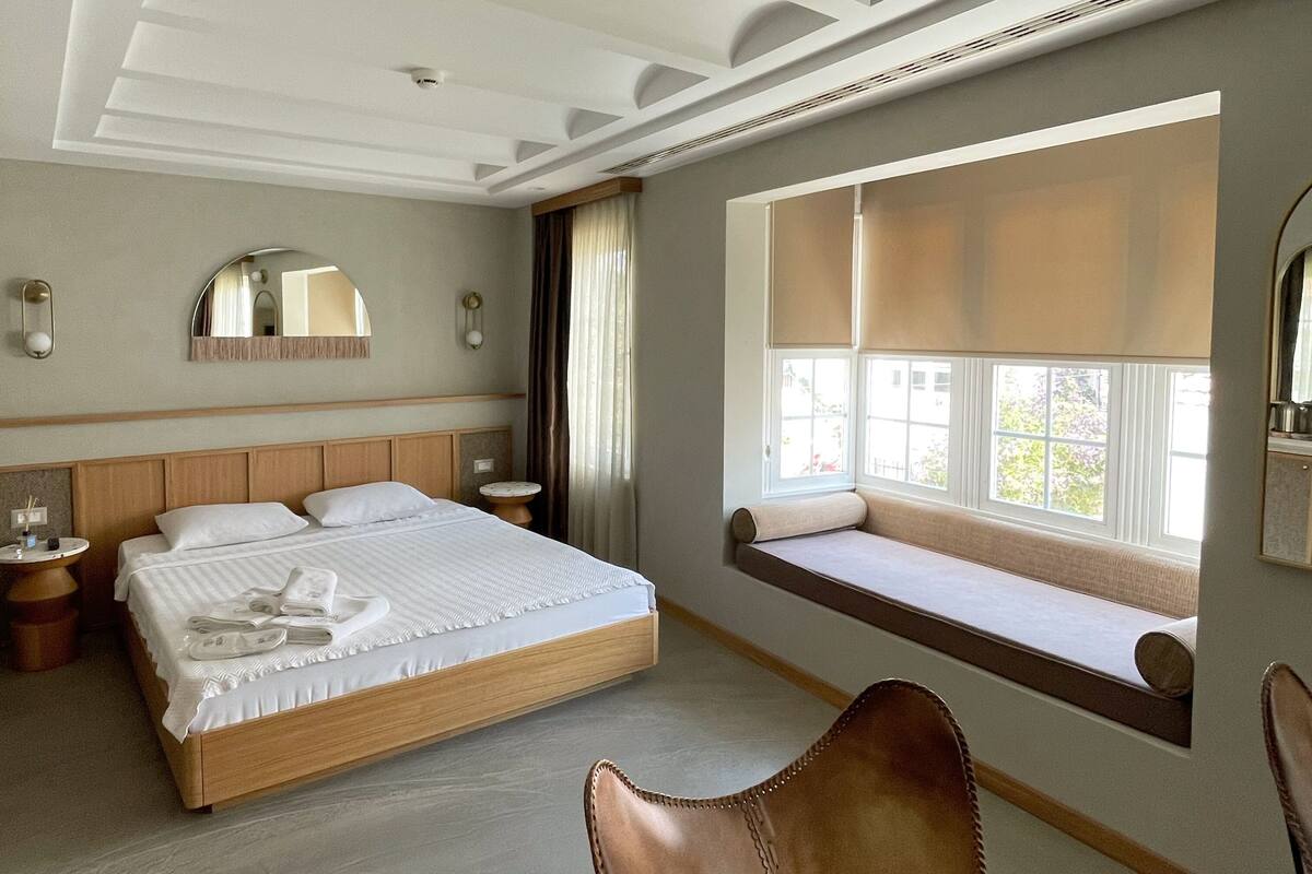 A bedroom with a large bed, a window seat, and a chair.