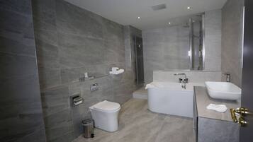 Un baño moderno con bañera, dos lavamanos y un inodoro.