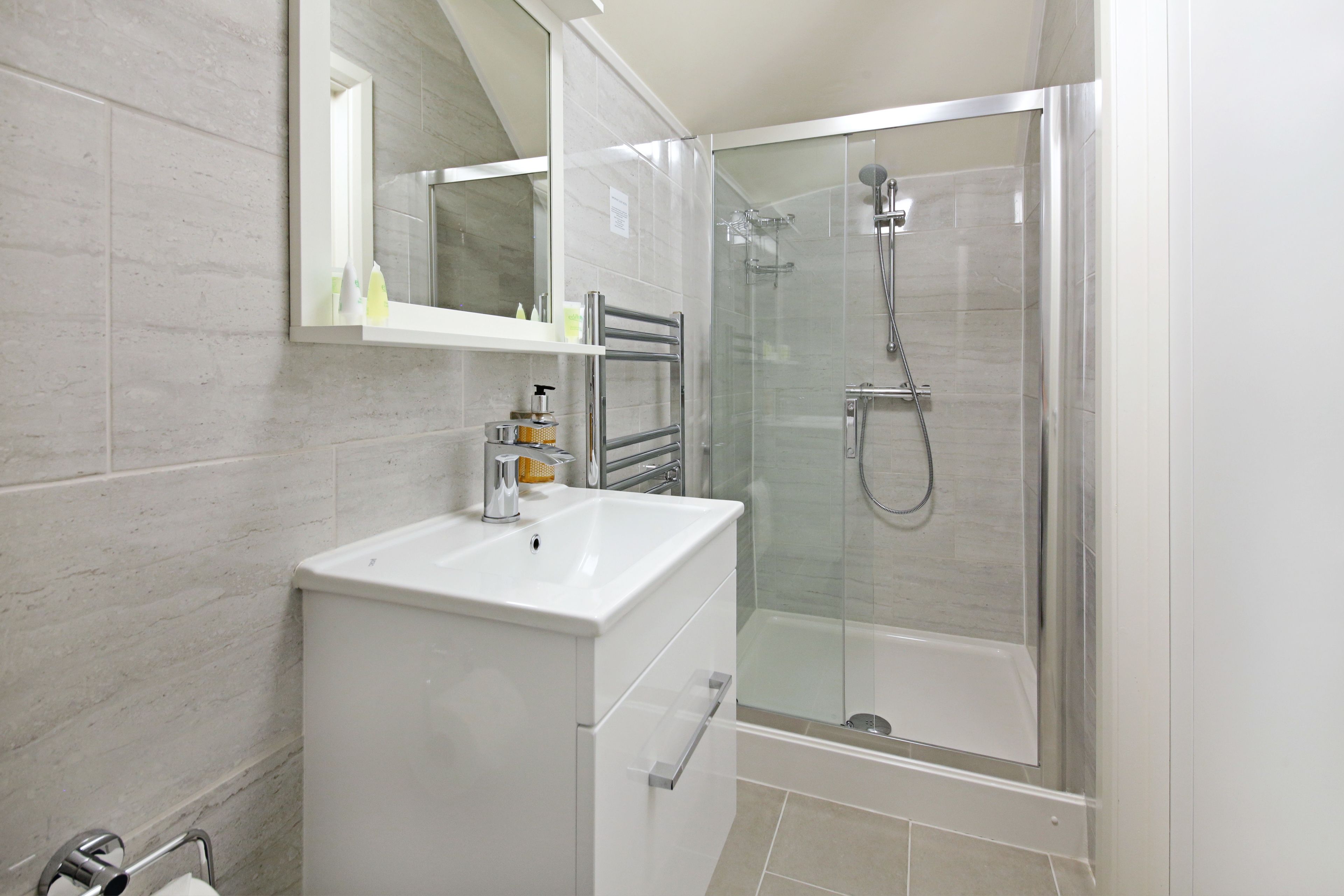 A modern bathroom with a glass-enclosed shower, a white sink, and a mirror above the sink.