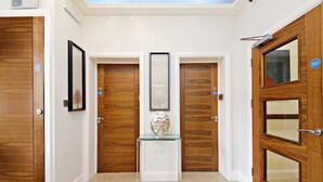 A hallway with wooden doors, a glass table with a decorative object, and a framed picture on the wall. - Imperial Guest House (Hounslow)
