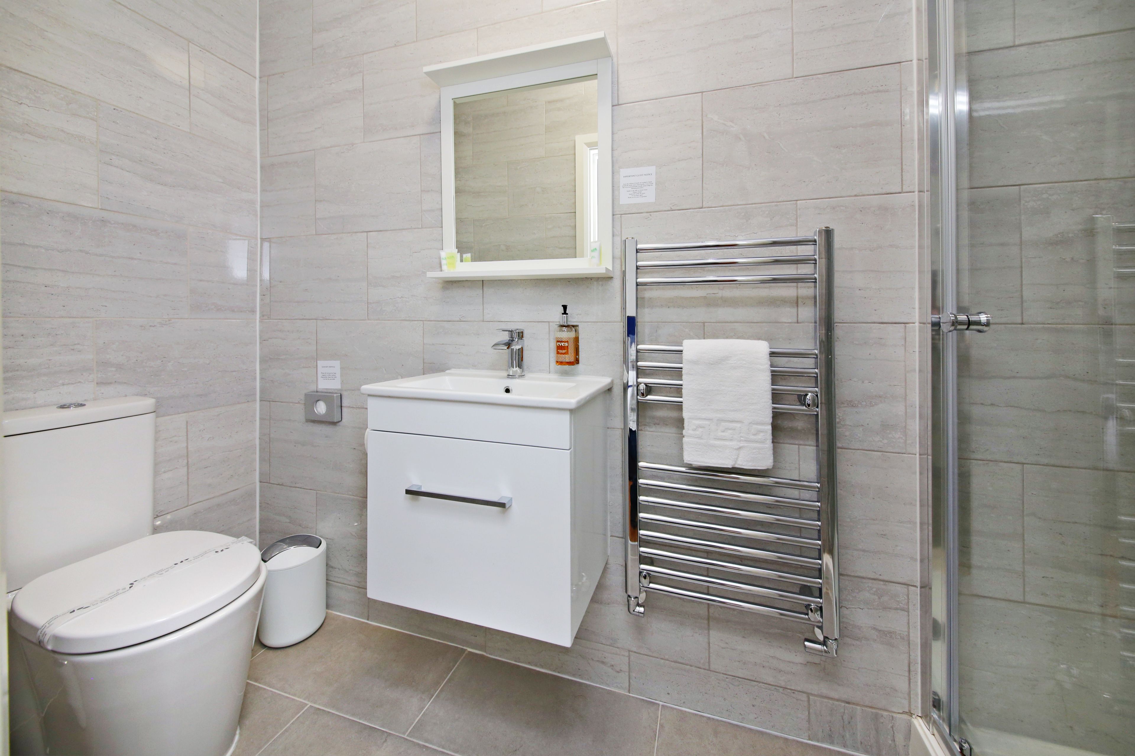 A modern bathroom with a toilet, sink, and glass shower enclosure.