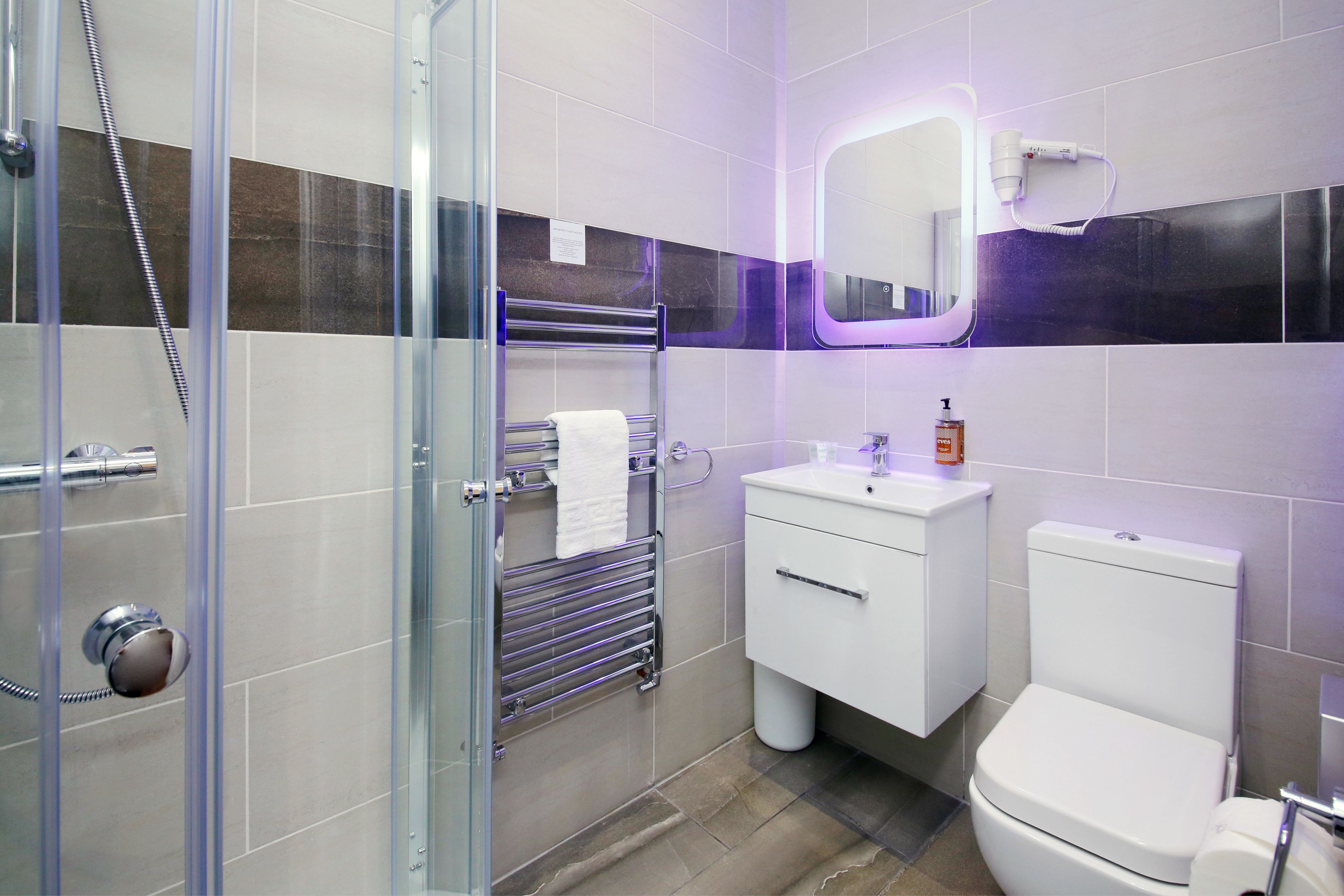 A modern bathroom with a glass shower enclosure, a white sink, and a toilet.