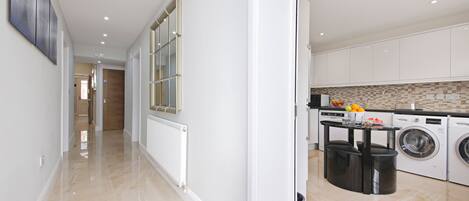 A modern kitchen with built-in appliances, a central island, and a view into the adjacent living area.