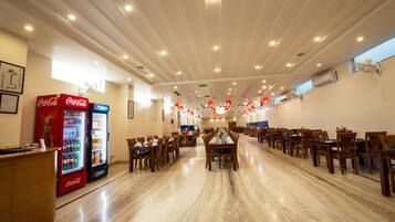 A spacious dining area with multiple tables and chairs, a reception desk, and vending machines.