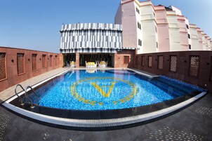 Una piscina con diseño geométrico, rodeada por un edificio de fachada moderna y pared exterior con motivos decorativos.