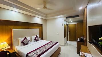 A hotel room with a large bed, a desk, a TV, and a wardrobe.
