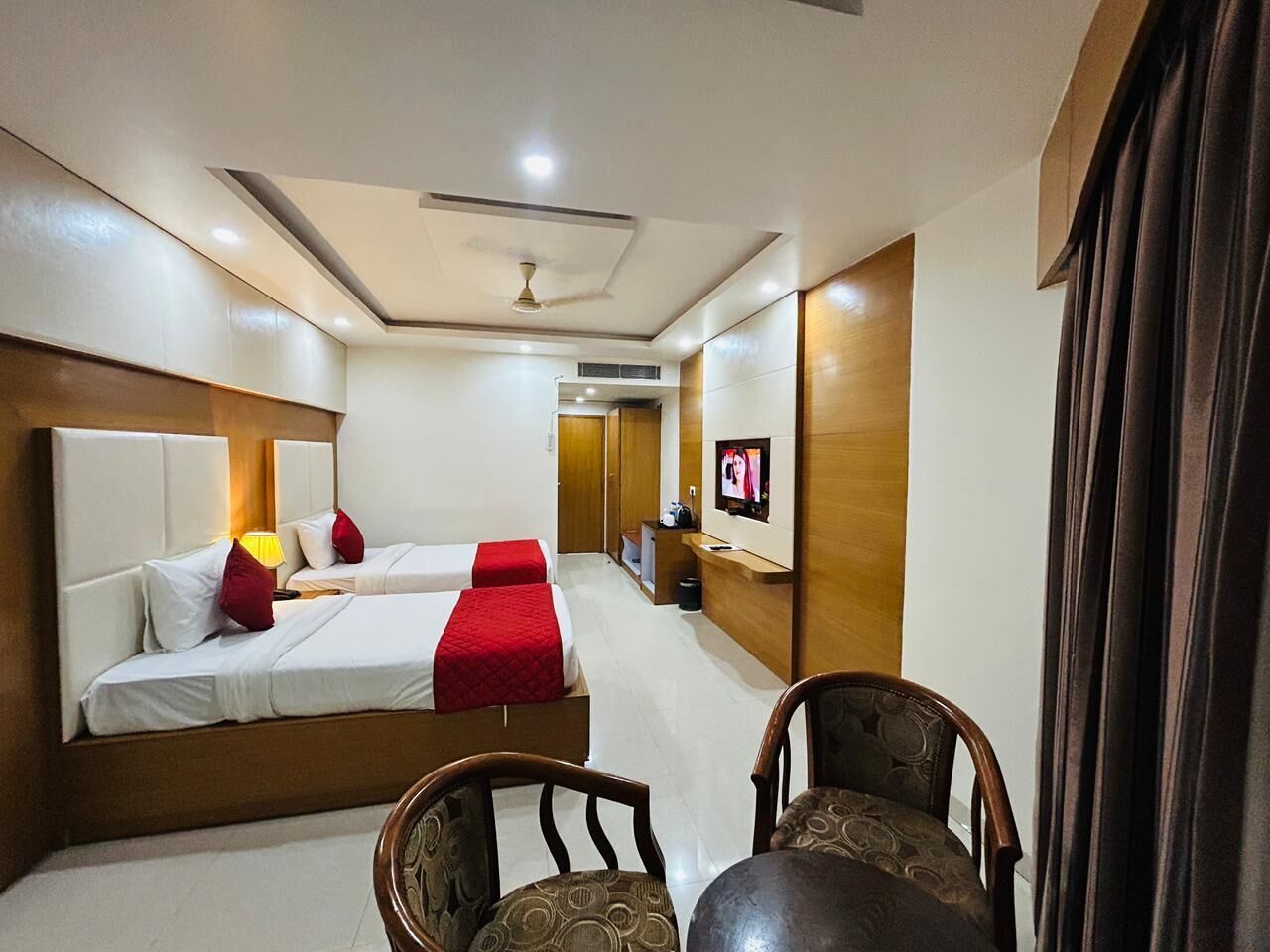 Habitación de hotel con dos camas, un televisor, un escritorio y una silla.