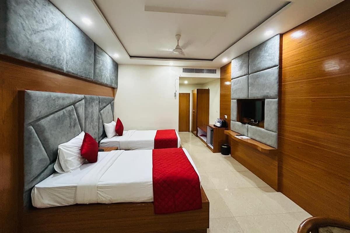 Ein Hotelzimmer mit zwei Betten, einem Fernseher, einem Deckenventilator und einer Wand mit Holzelementen.