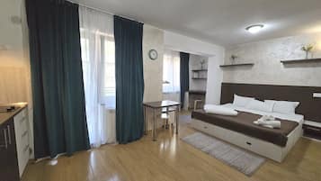 A modern hotel room with a bed, a desk, and a chair.