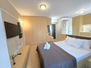 A hotel room with a bed, a TV, a desk, and a bathroom. - Decebal Residence Apartments (Bucharest)