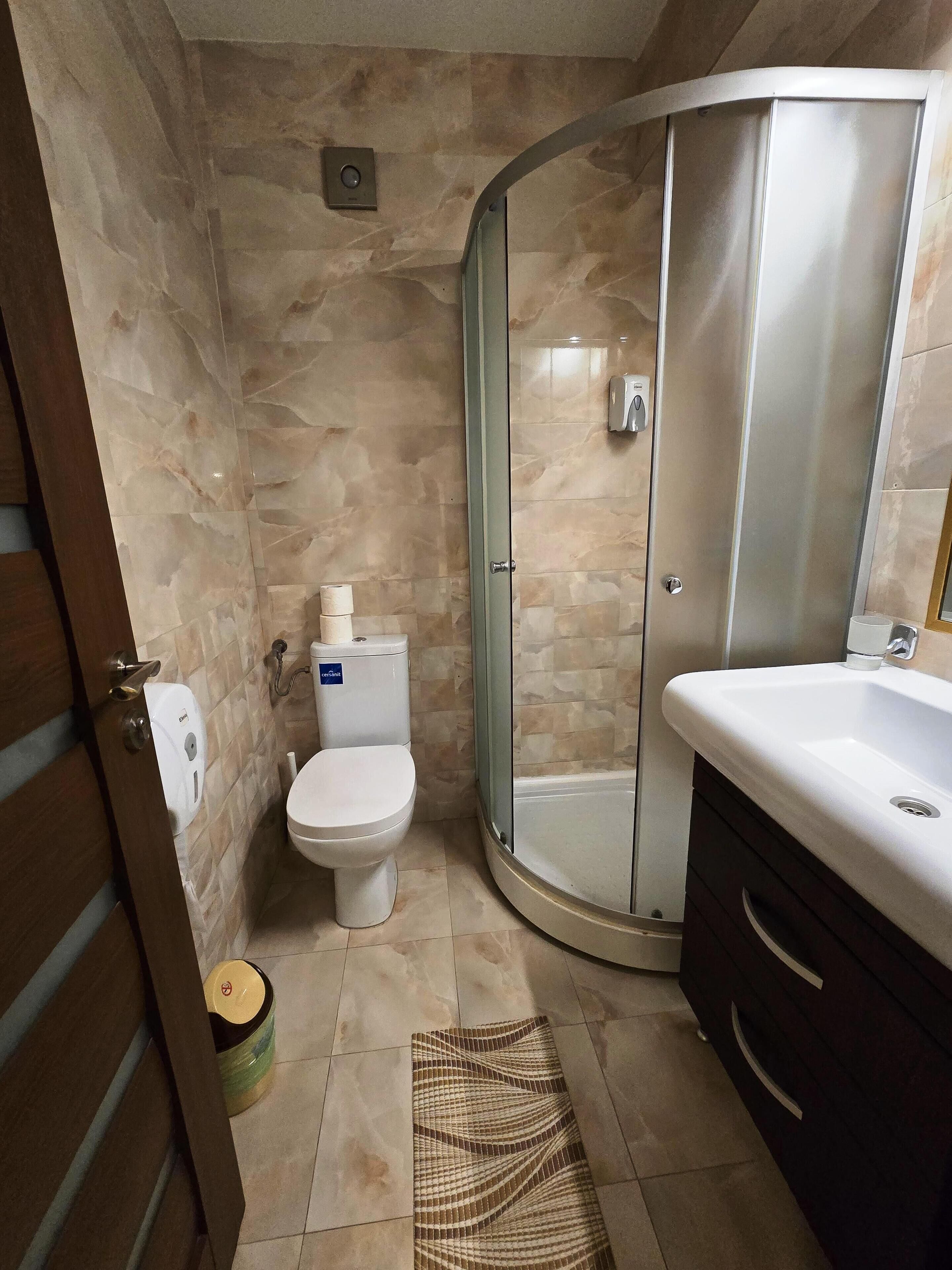 A bathroom with a toilet, a glass shower enclosure, and a sink.