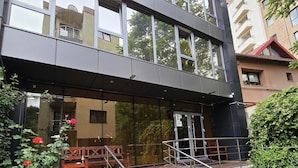 Un bâtiment moderne doté d’une façade en verre, d’un escalier recouvert d’une moquette verte et d’un banc à l’extérieur.