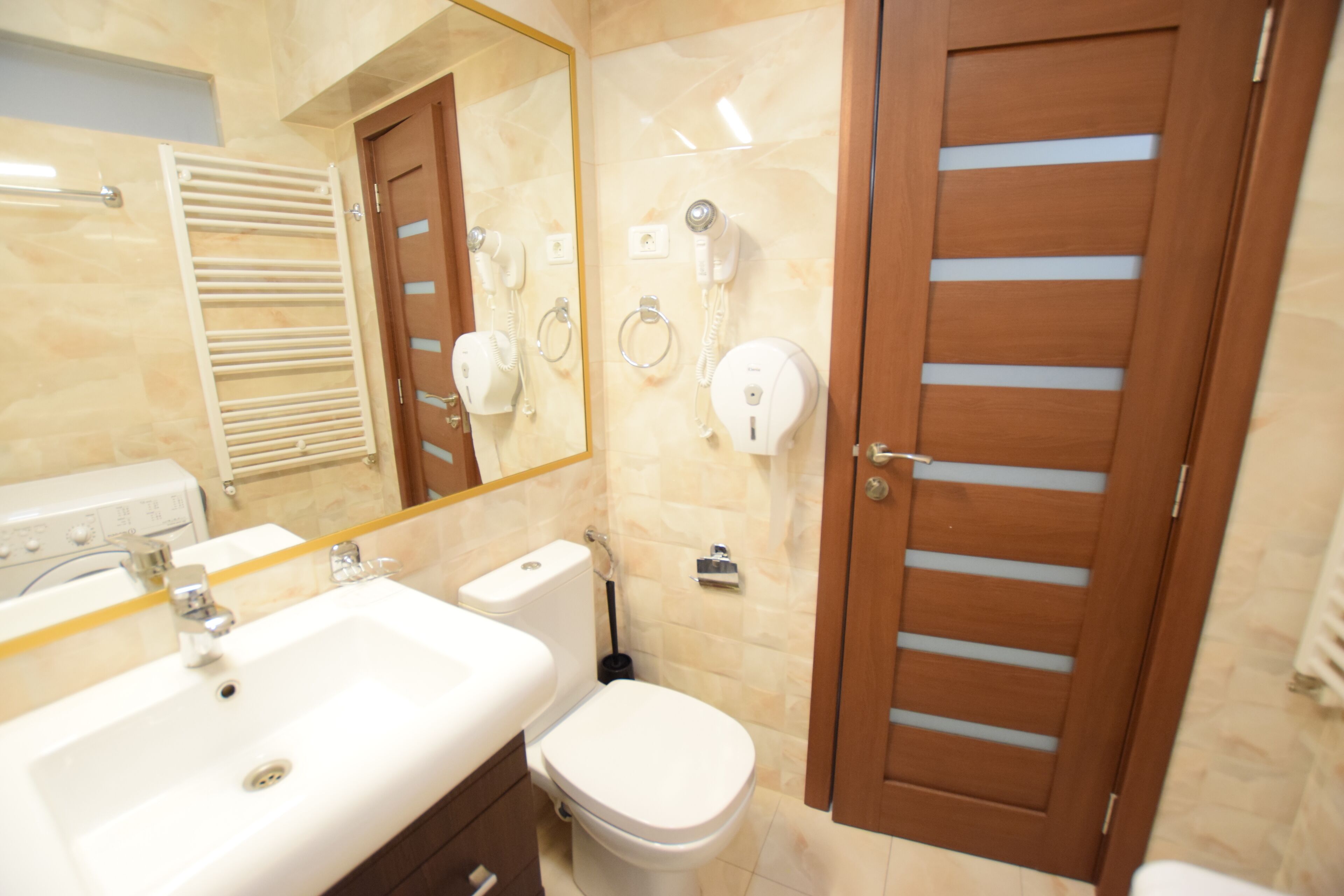 Une salle de bain équipée d’un lavabo, de toilettes et de deux sèche-cheveux fixés au mur.