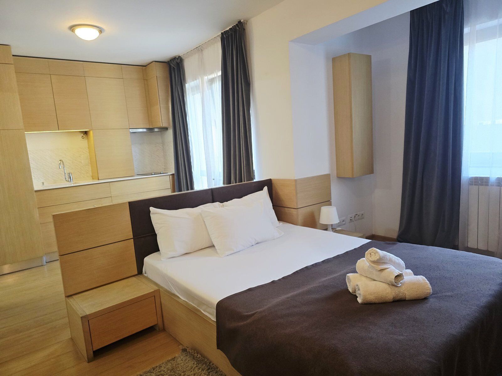 Habitación de hotel con cama, mesita de noche, espejo, ventana con cortinas y armario empotrado.
